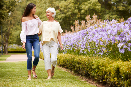 Young woman and elderly woman walking together through the symptoms of alzheimers or dementia