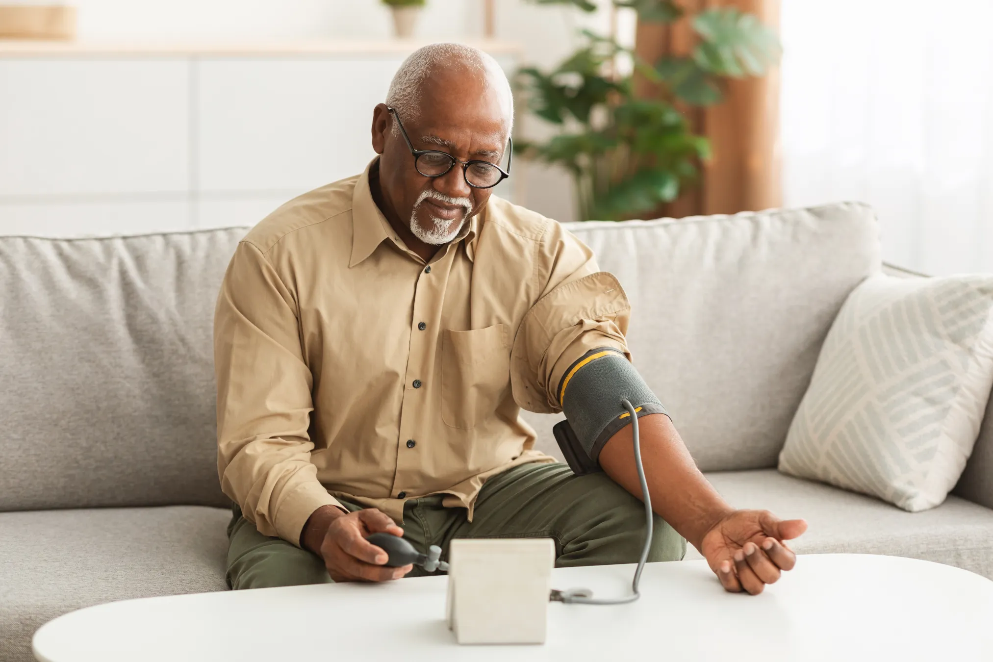 Man sitting on couch testing blood pressure